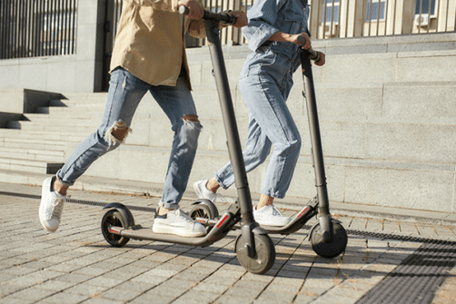 Bilde som viser to unge kjørere på elsparkesykkel i et type bybilde