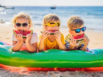 Barn som spiser vannmelon i vannkanten - trygg sommer