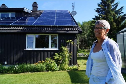 Bildet viser Rikke Iversen Sæhlie ved boligen med solcelleanlegg på taket