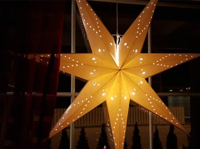 adventstjerne i papp lyser opp i vinduet
