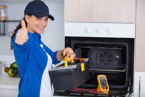 Bilde av ung kvinnelig elsikkerhetsingeniør ved komfyr i kjøkken