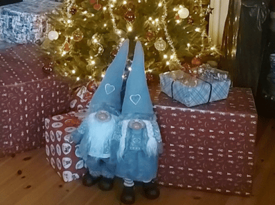 Bilde viser et nissepar med julegaver under et juletre