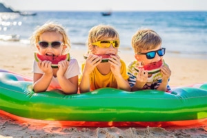 Barn som spiser vannmelon i vannkanten - trygg sommer